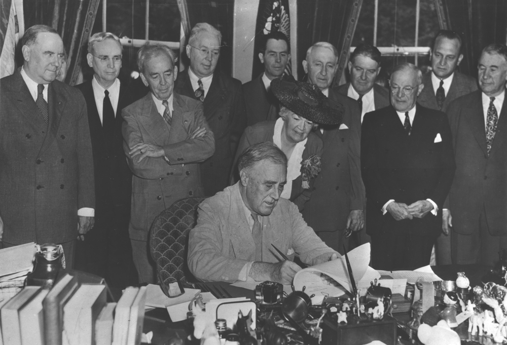 President Roosevelt signing the GI Bill surrounded by others