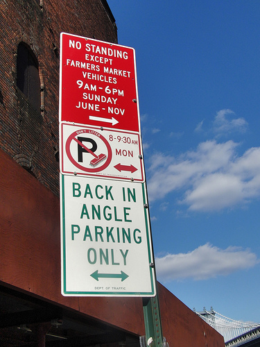 Several signs with parking regulations on the same poll.