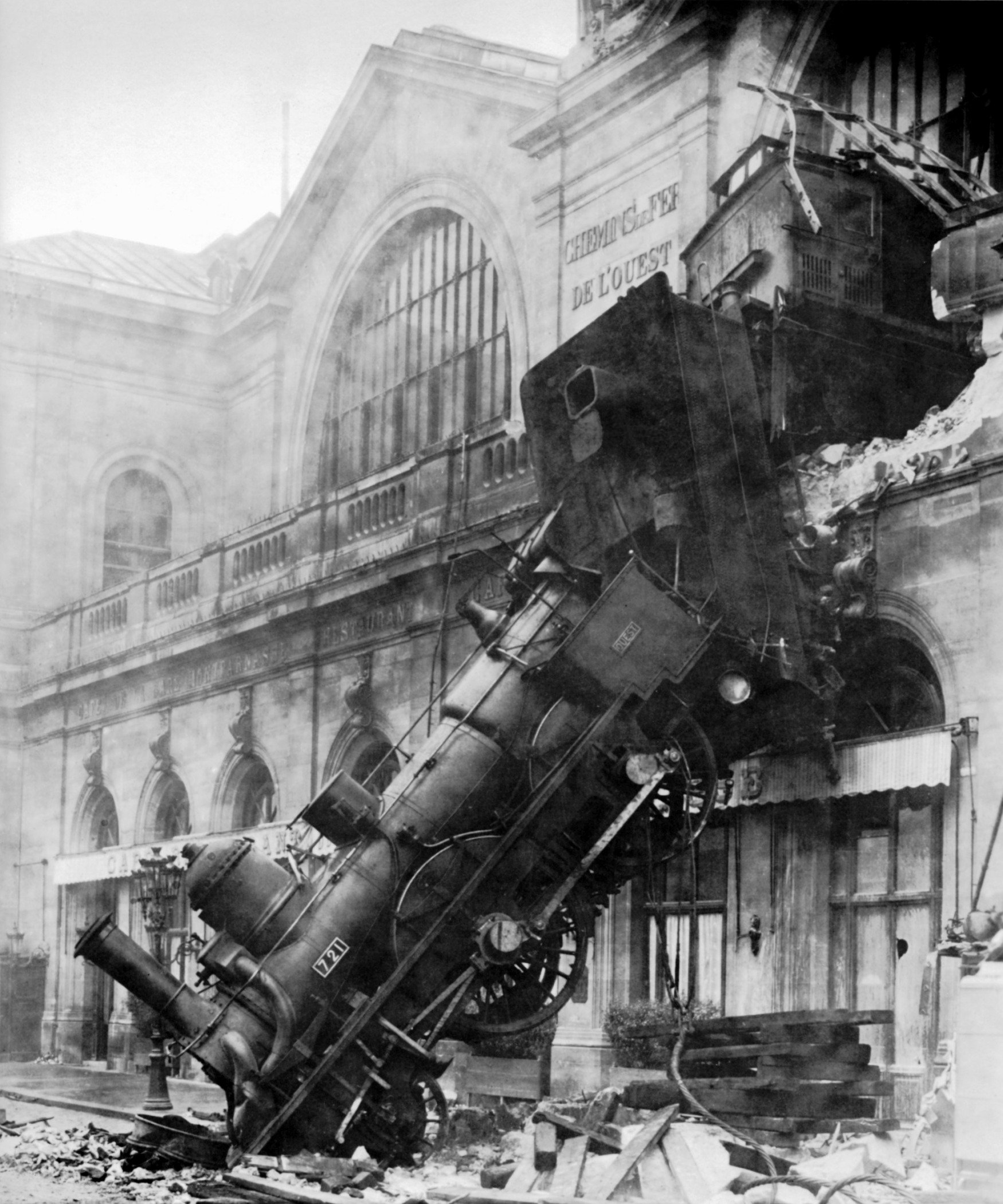 Photo of a train engine that has crashed comletely through the wall of a train station.