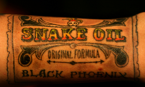 Photo of a multi-colored tatoo that reads "snake oil."