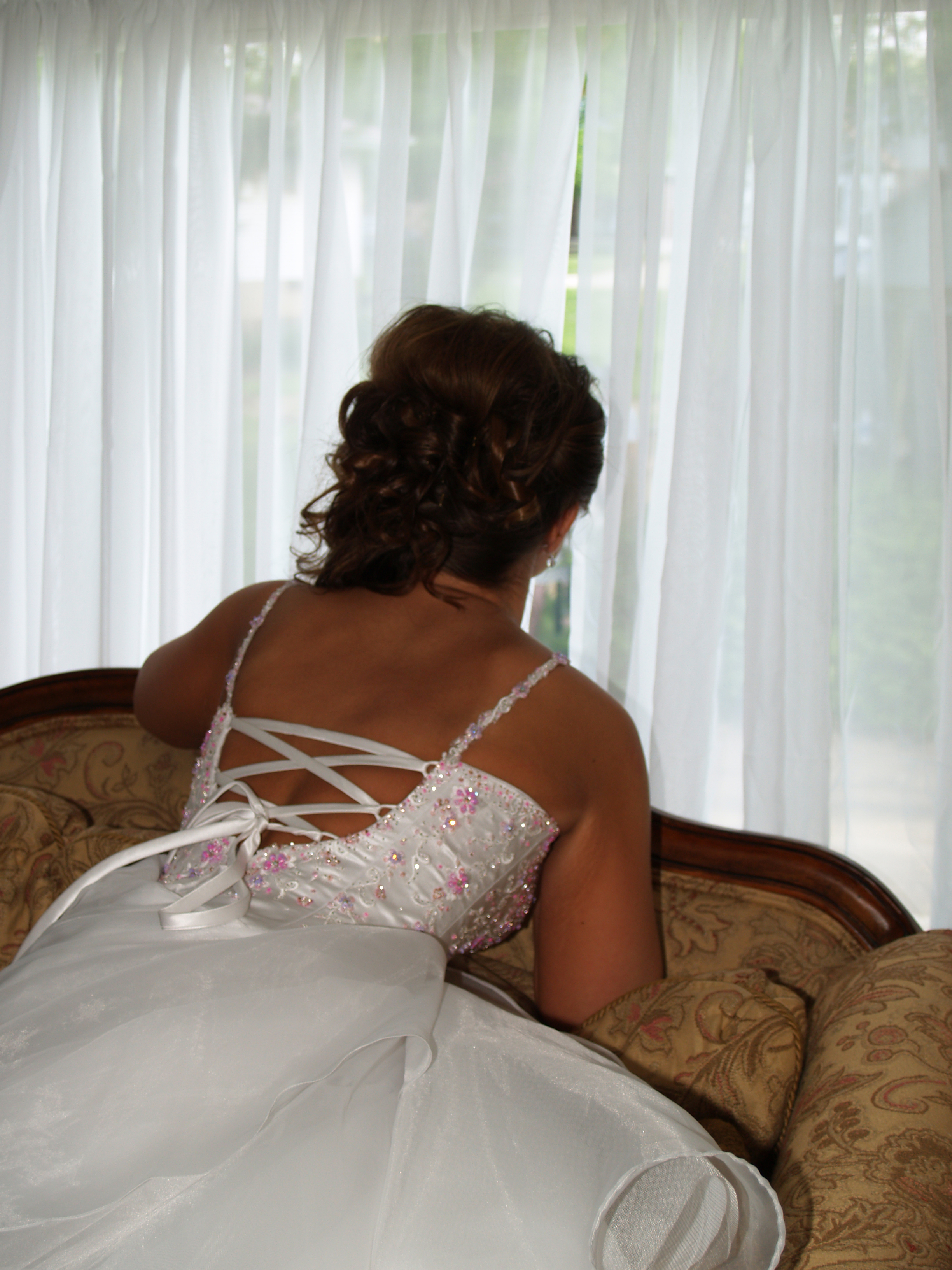 Photo of back of bride as she looks out the window expectantly.
