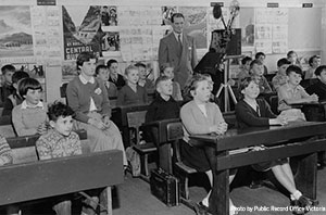 1950's photo of teacher with a film projector in a class of young children.