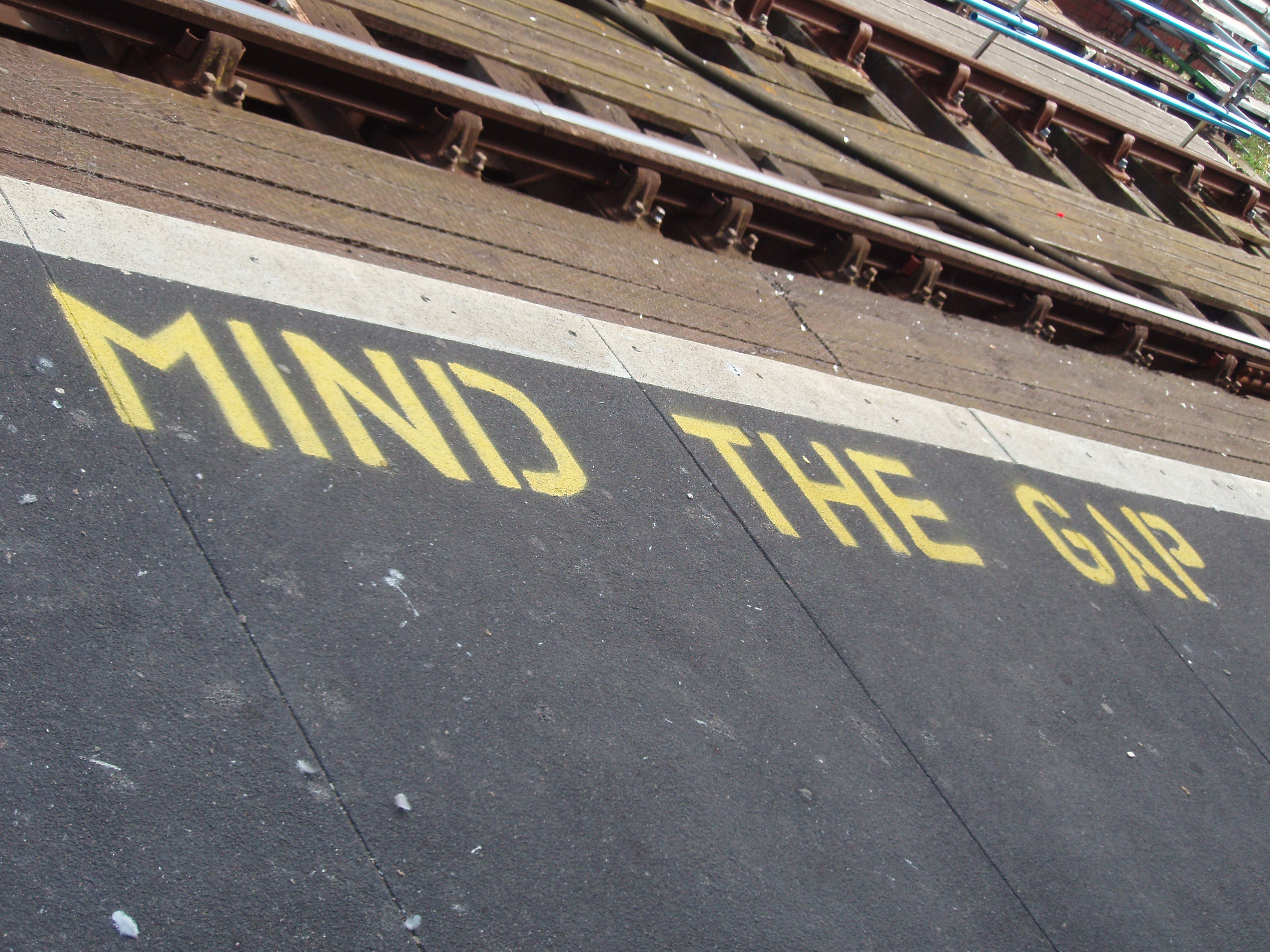 Railroad tracks with a sign reading "mind the gap" to warn passengers boarding the train.