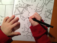 childs hands connecting the dots in coloring book.