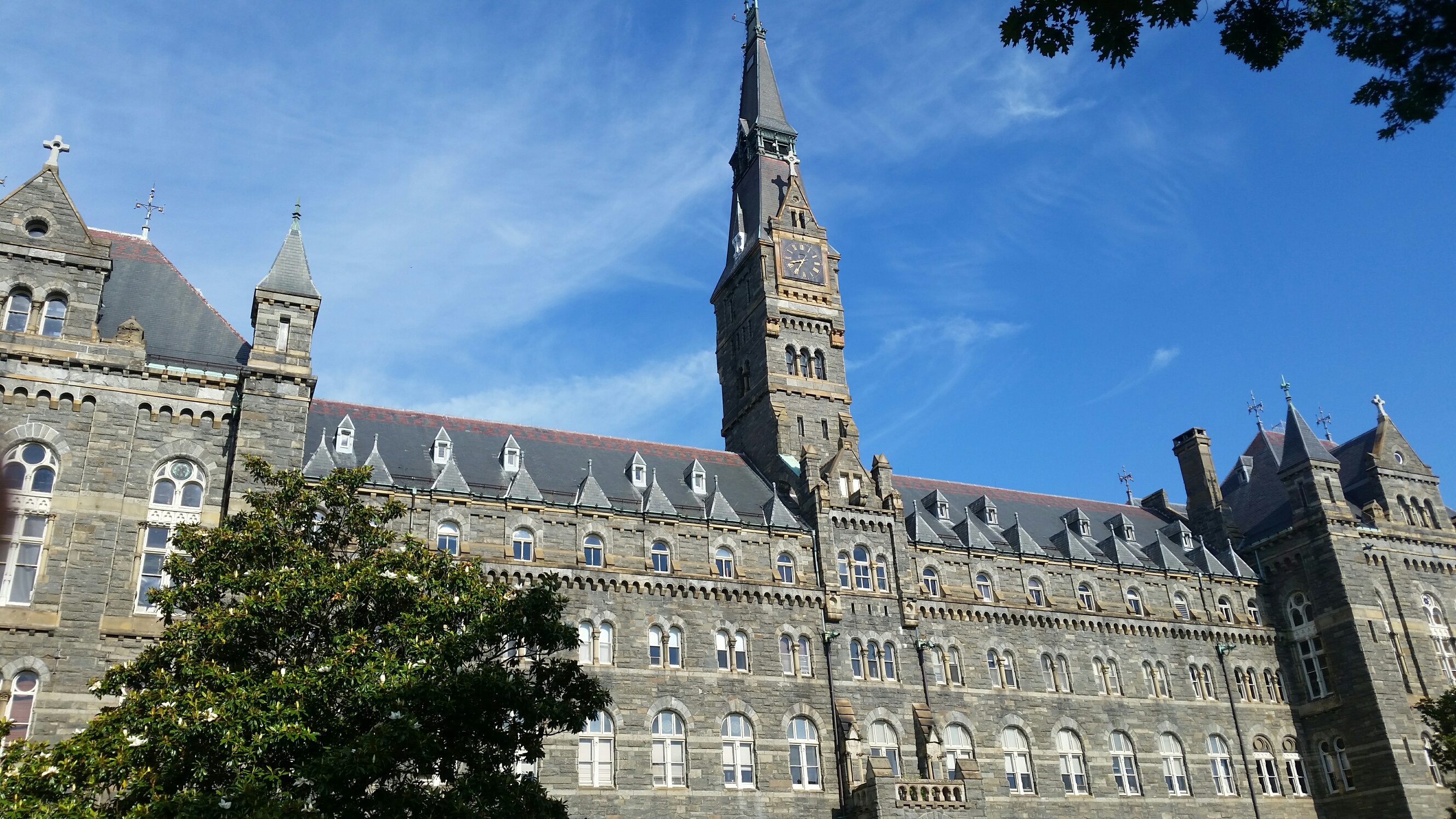 Picture of the stately main building at Georgetown University. It looks slightly like a castle with a tall, narrow clock tower in the middle.