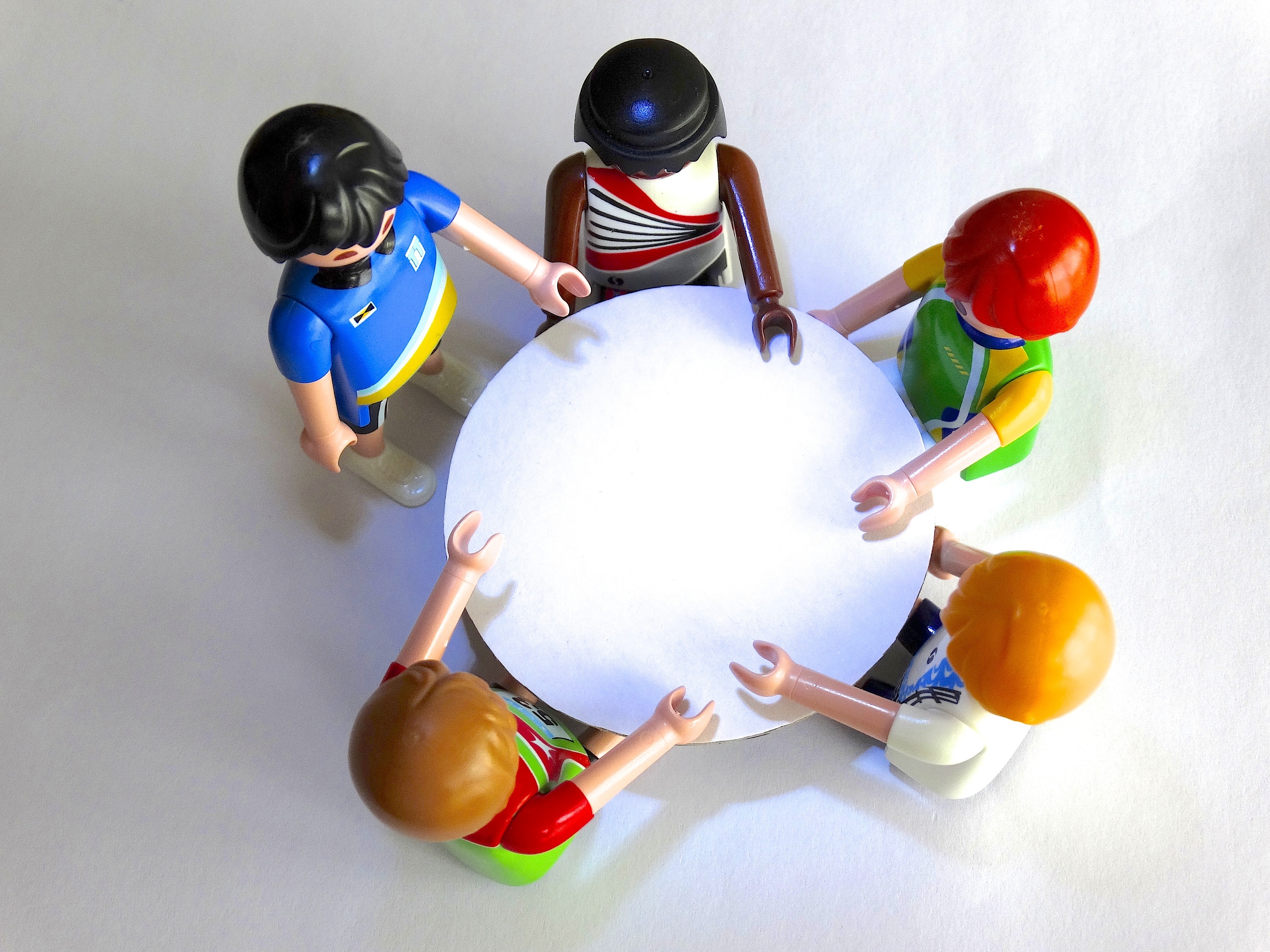 Small, lego figurines in a circle around a mini table.