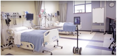 Image of two hospital beds and a tablet attached to wheels (robotics) moving through the room.