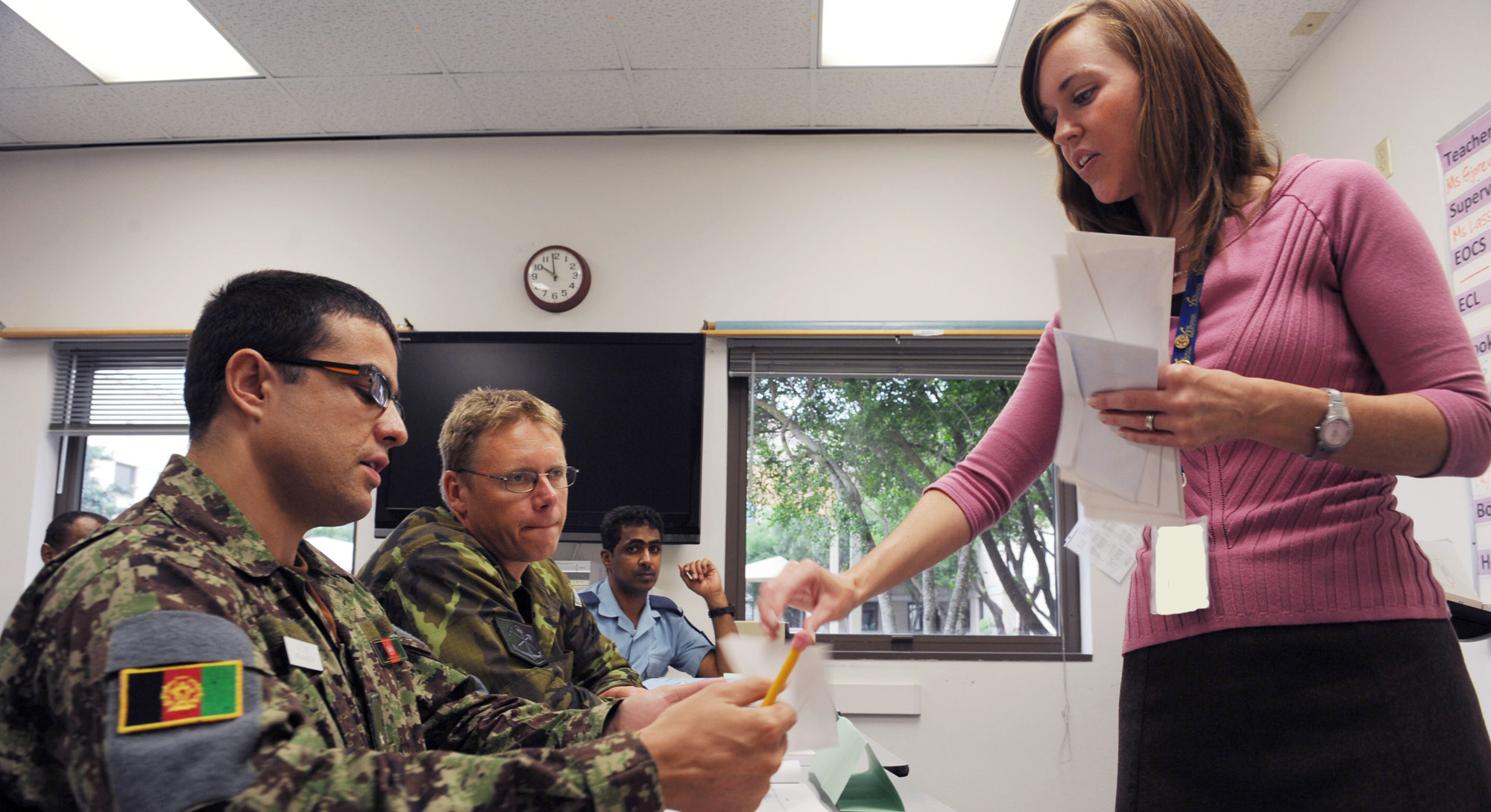 instructor hands two military students an assignment