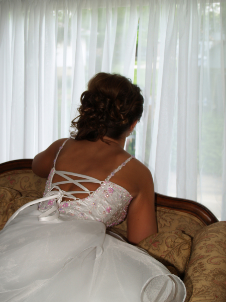 A woman in a bridal gown staring out the window.