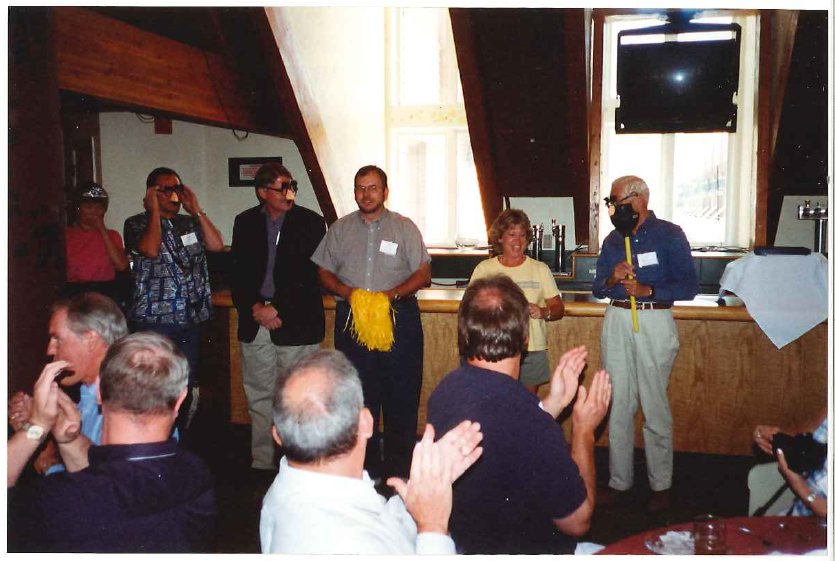Photo of the graduation ceremony at the now defunct Manager of Distance Education Institute, an early WCET event. From the right: John Witherspoon with the standard (a plunger), Darcy Hardy, Russ Poulin (with the pom poms), Fred Hurst, Ray Lewis, mystery woman in an awesome tiara. Kazoos were used to play 