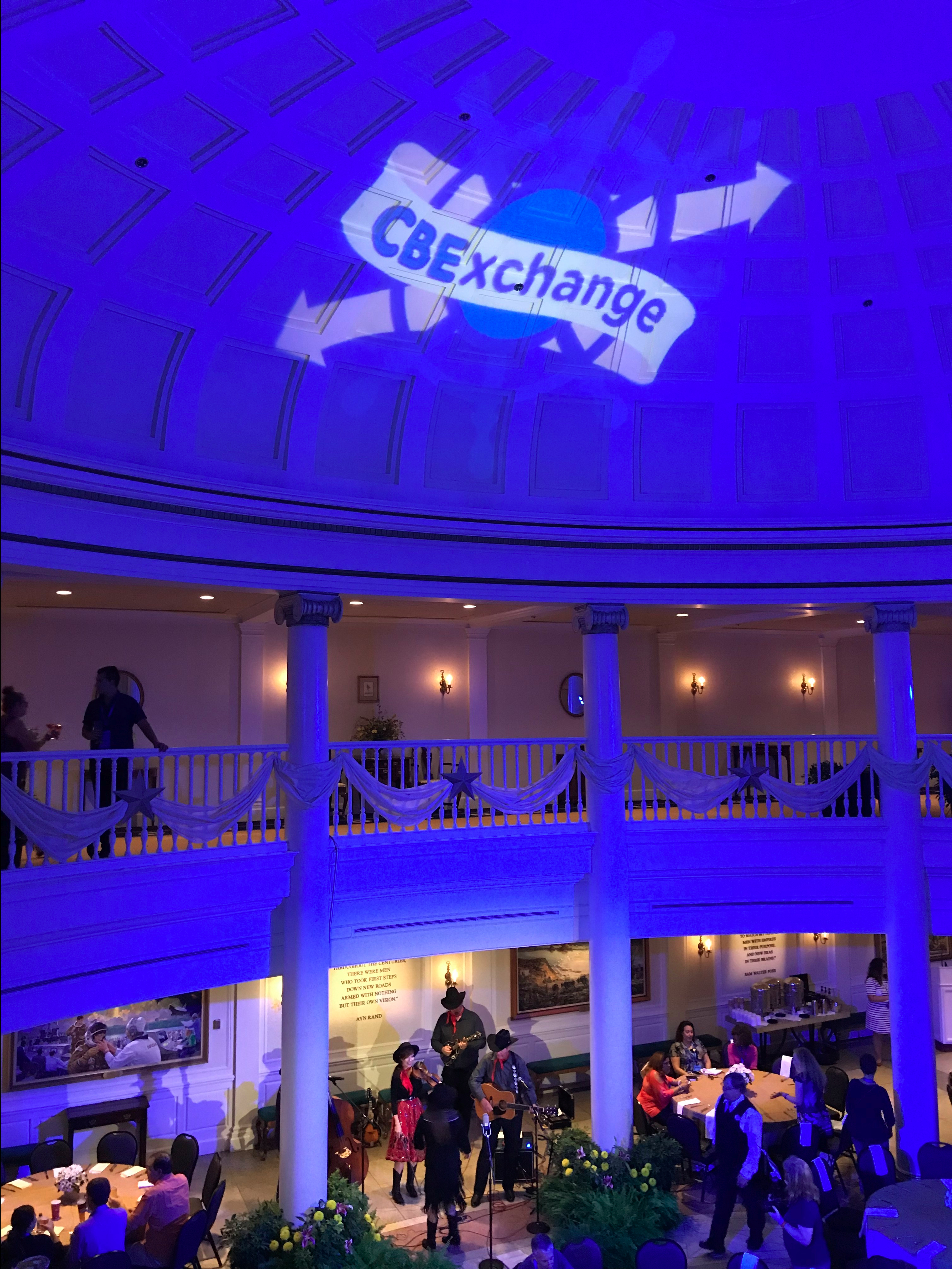 Large room with lighting changd to blue and the CBEExchange logo projected onto the ceiling.