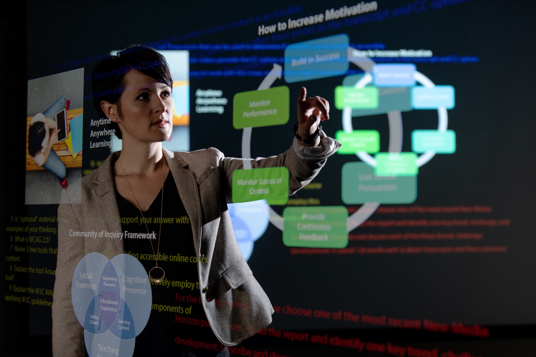 Picture of Generation Z student studying and touching a large computer screen. The computer screen contains a circular graph that shows how to increase motivation. This picture is an ideal learning environment for a Gen Z student.