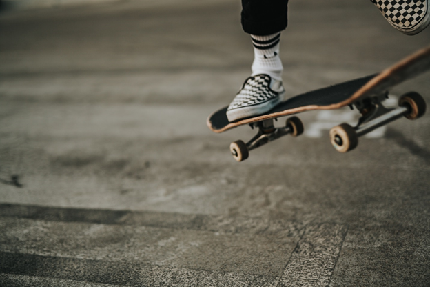 A person on a skate board jumping over sidewalk