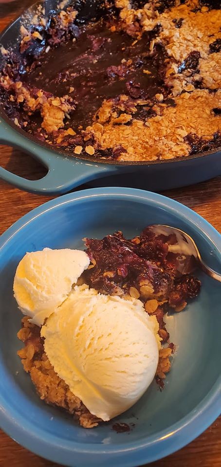 photo of a castiron pan with blueberry cobbler and ice cream