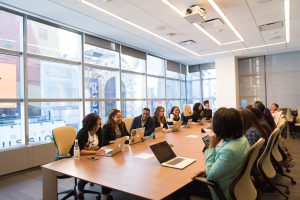 a group of individuals around a large table having a meeting