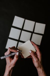 several sticky notes laid out on a table, someone preparing to write on a note.