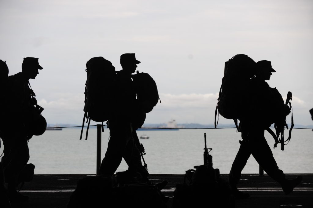 military officers walking in front of a body of water