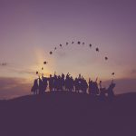 group of graduates throwing hats at dawn
