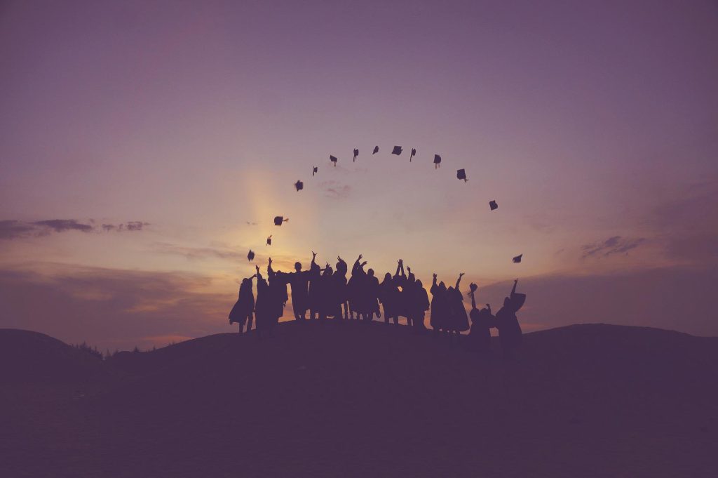 group of graduates throwing hats at dawn