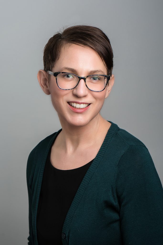 Anne Reed photo - Young woman with glasses smiles at the camera.