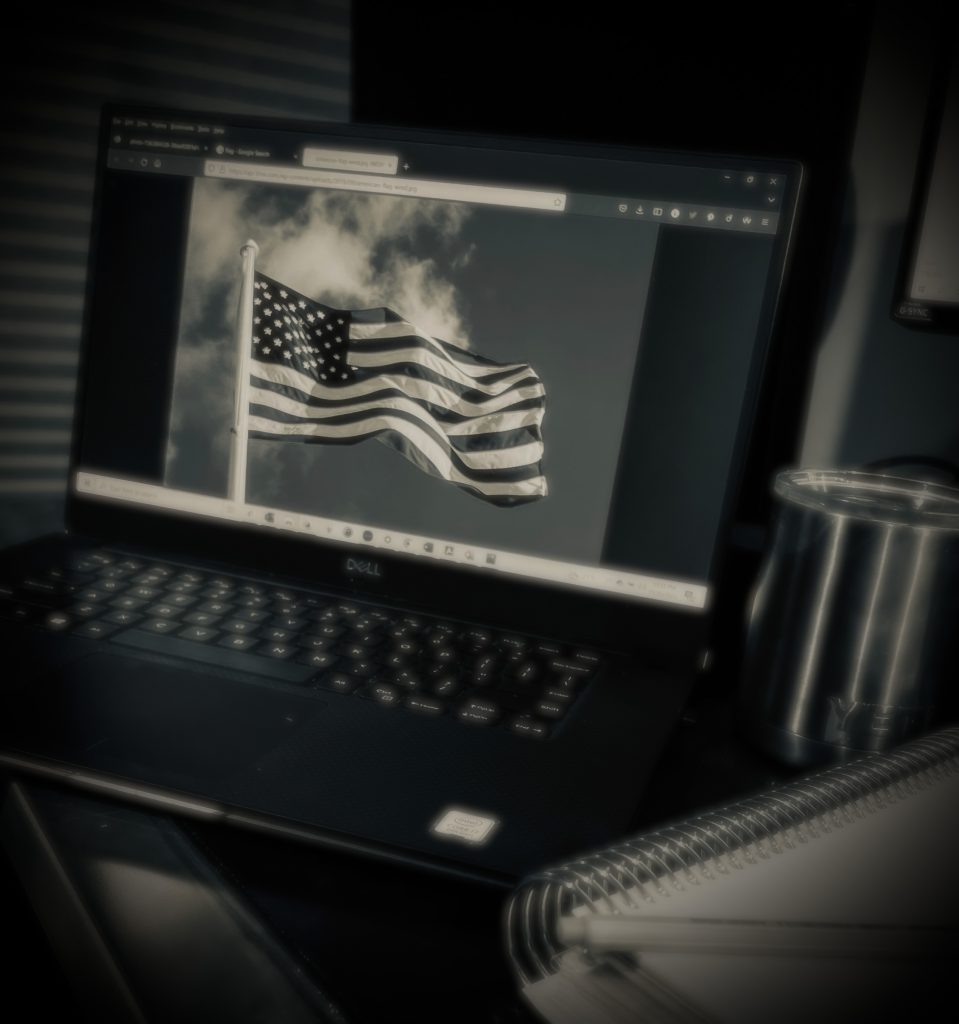 black and white photo of a laptop with the photo of a flag on the screen.