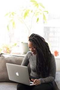 A woman sitting in a bright room looks at her computer screen. 