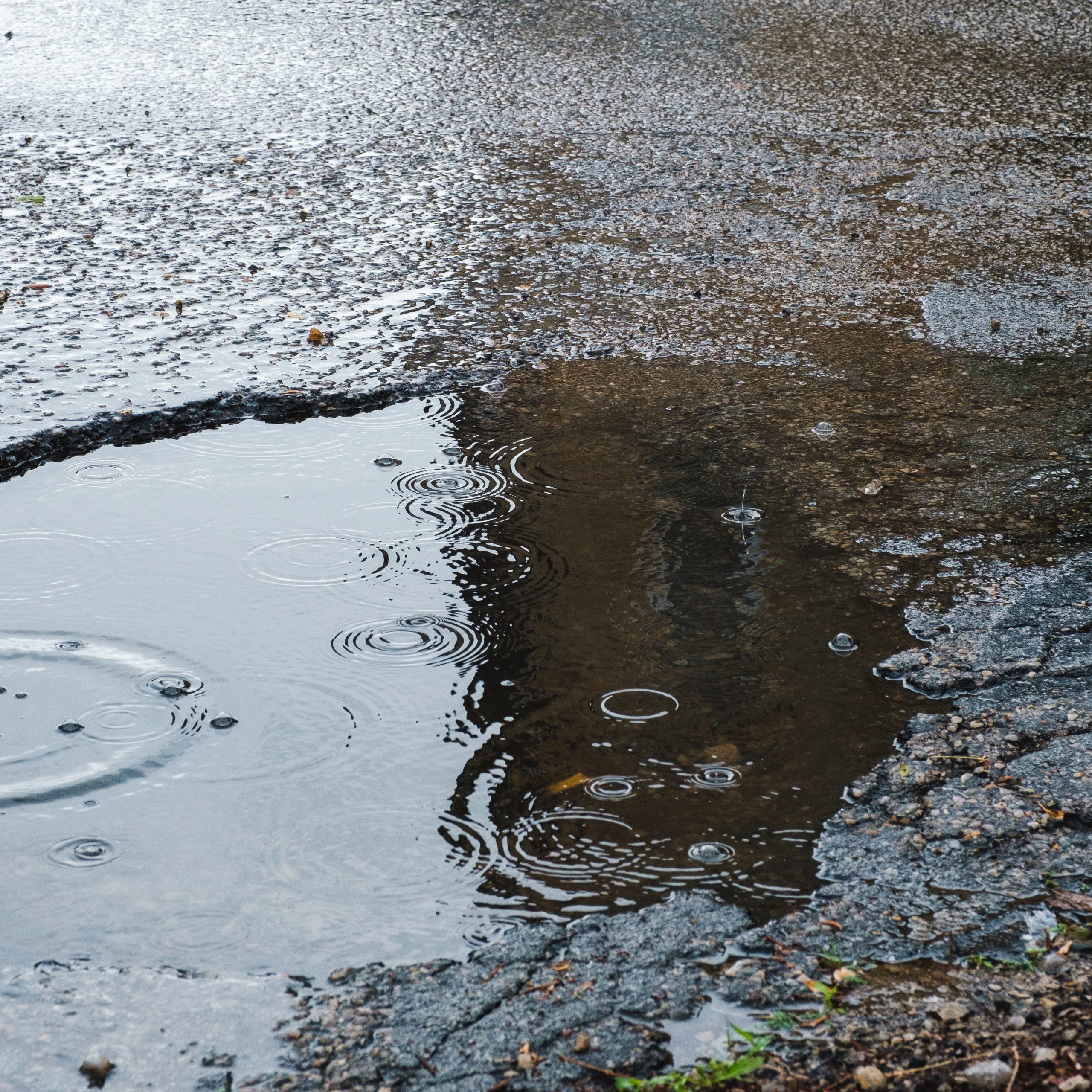 Large pothole in a road filled with water