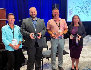 Group of individuals holding crystal award plaques. 