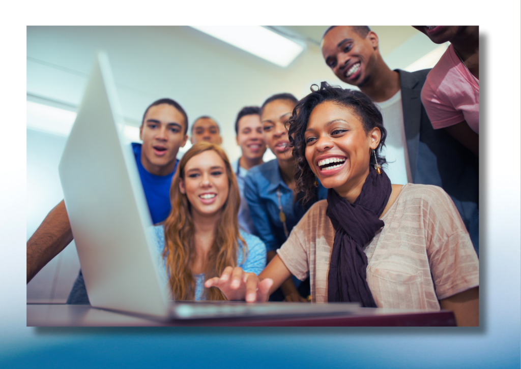 Group of excited seeming college students gathered around a laptop.