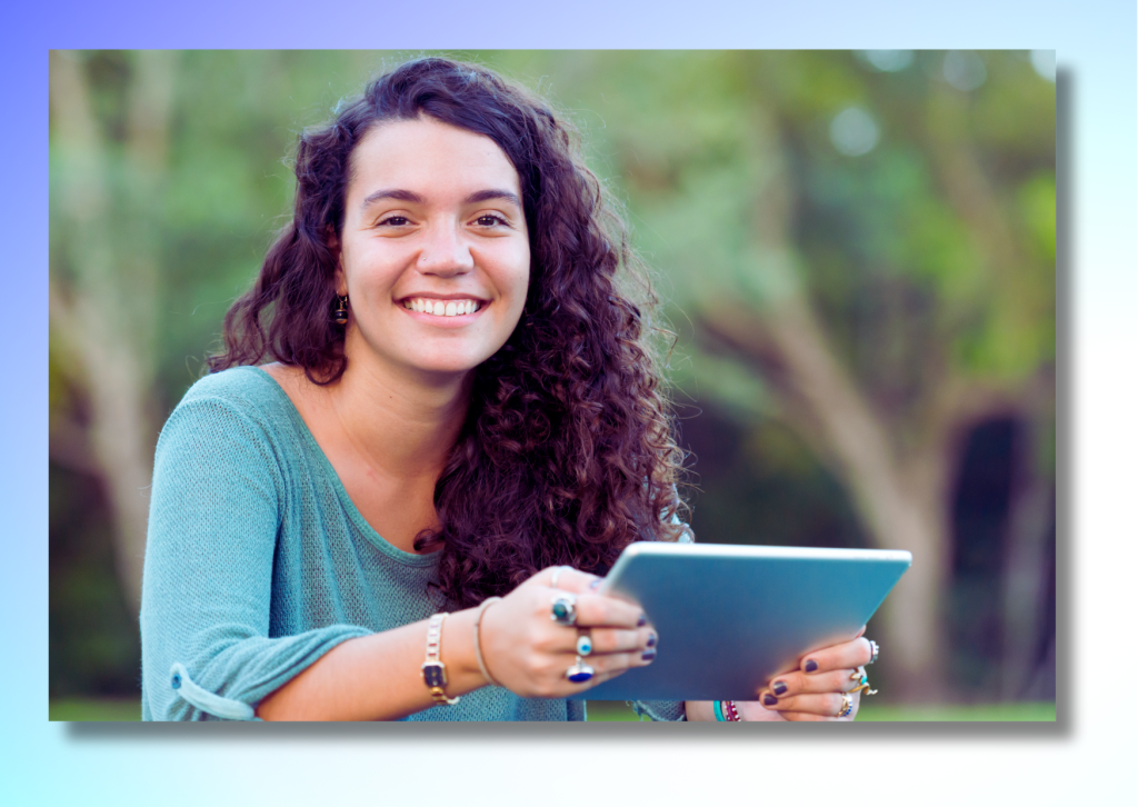 A college student smiling while holding a tablet