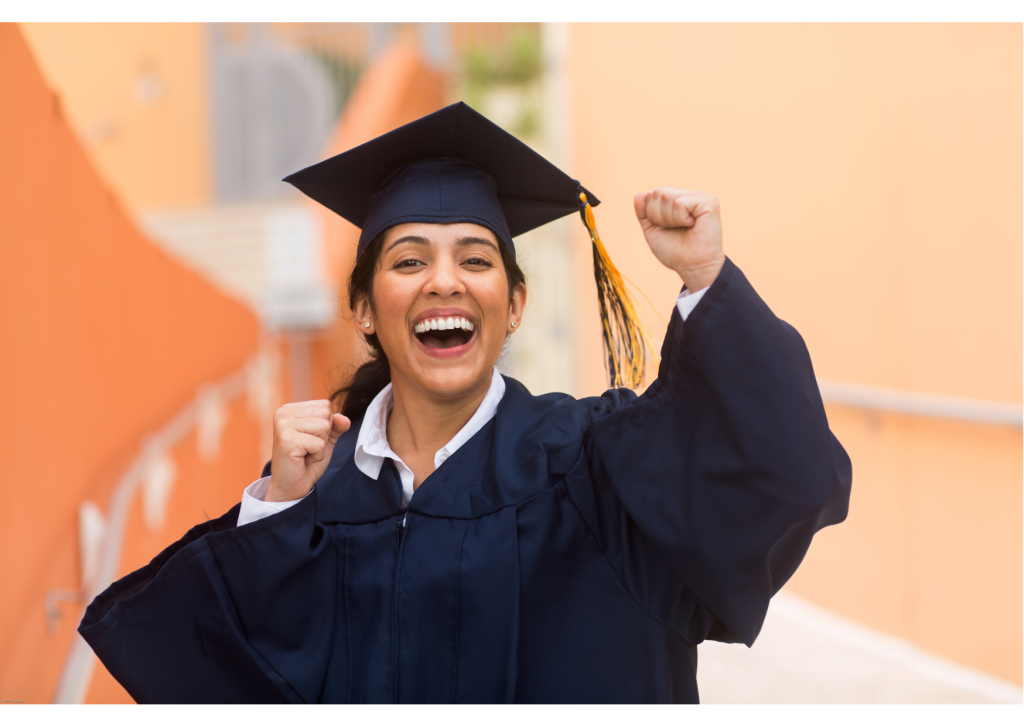 college-aged student dressed in graduation regalia expressing excitement with arms in air