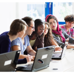 students working on laptops around a large table