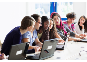 students working on laptops around a large table