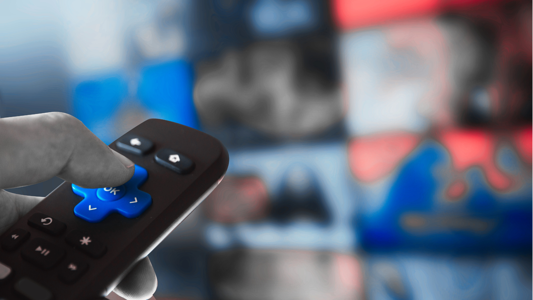 Image of a hand holding a tv remote pointed toward a blurry television 