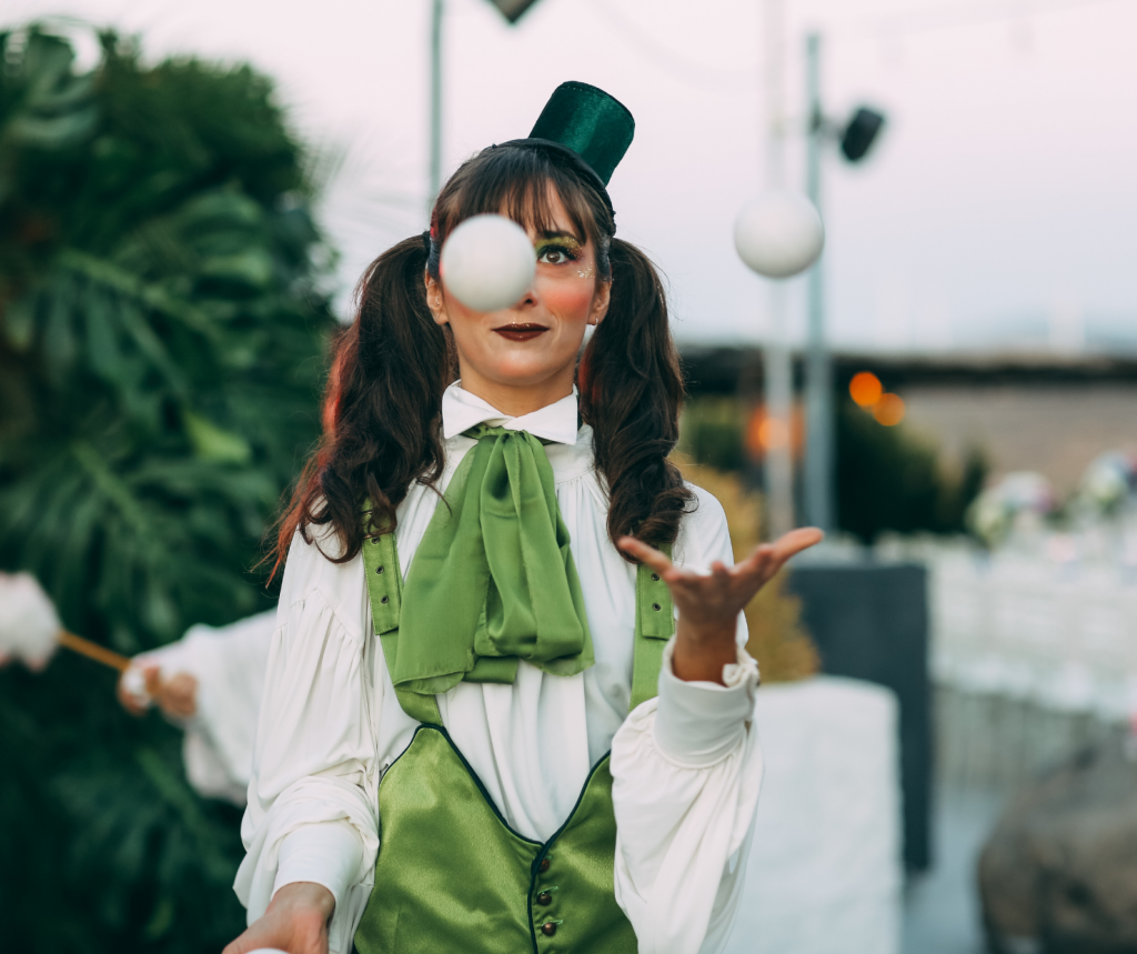 A young woman in a clown outfit juggling
