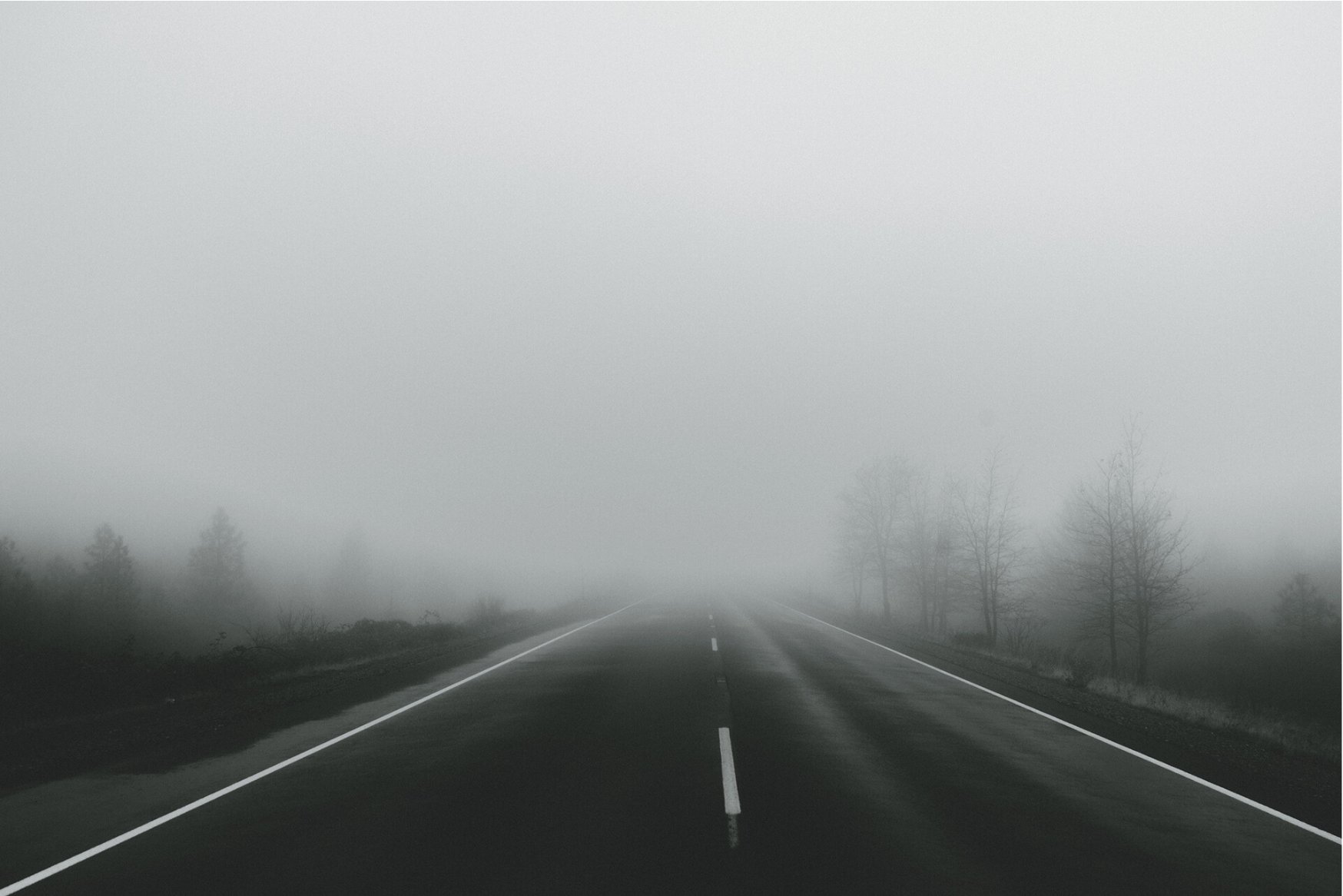 A road leading toward a large fog bank