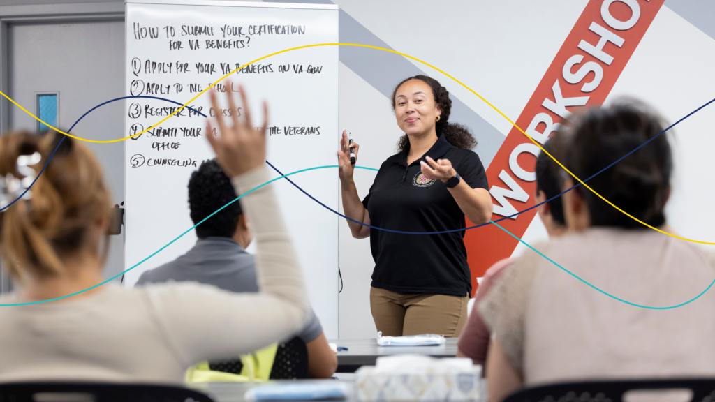A smiling instructor leads a workshop for a group of students, standing next to a whiteboard detailing the five steps for submitting a certification for VA benefits.