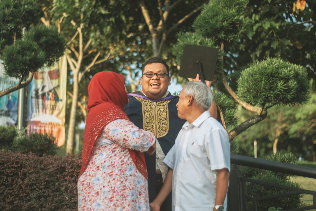 Adult graduating from college being embraced by his gray haired family