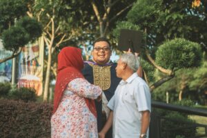 Adult graduating from college being embraced by his gray haired family