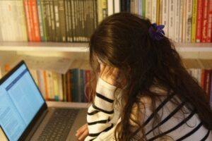 photo of woman with long brown hair looking at laptop with melancholy expression