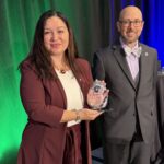 Rae Mancilla holds the glass WCET Sally M. Johnstone Award beside WCET Executive Director Van Davis.